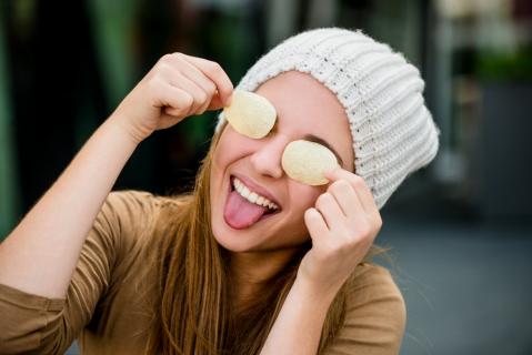 Mädchen mit Chips vor den Augen streckt Zunge heraus