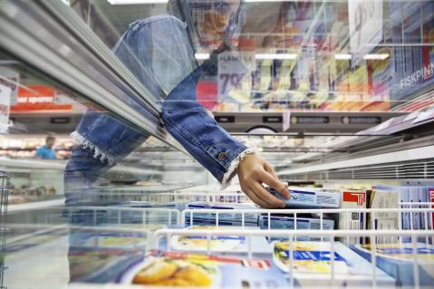 Frau greift in Kühltruhe mit Fisch-Produkten