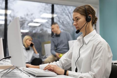Frau im Callcenter mit Kopfhörer und Mikrofon