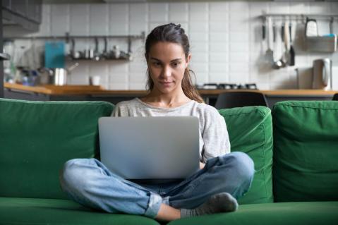 Frau mit Laptop auf grünem Sofa