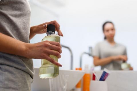 Frau mit Flasche Mundspülung in der Hand