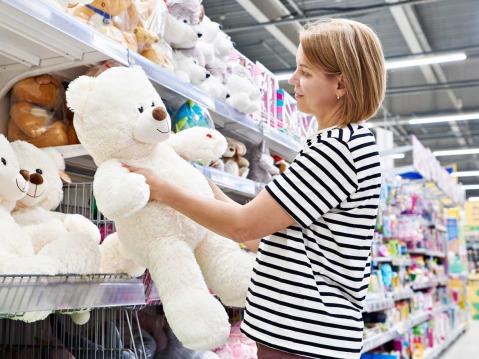 Frau kauft Teddybär in Spielzeugladen