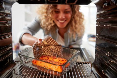 Frau schiebt Lachs in Backofen