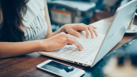 Frau tippt auf Tastatur eines Laptops