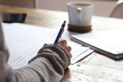 Frau hält Stift in der Hand und macht Notizen