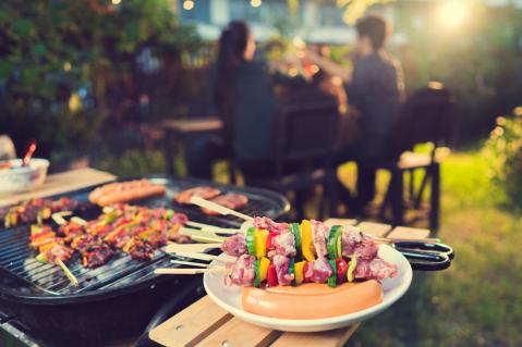 Grill mit Fleisch und Menschengruppe im Hintergrund