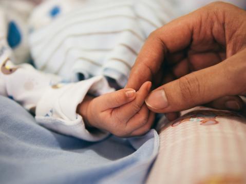 Erwachsener hält Hand eines Babys