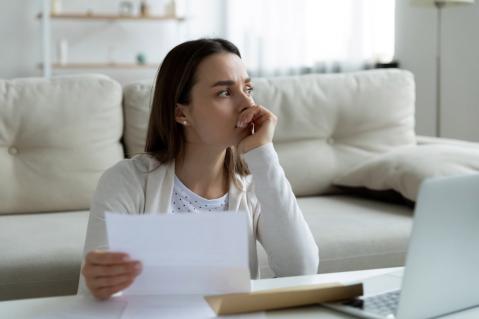 Junge Frau mit Brief in der Hand schaut nachdenklich