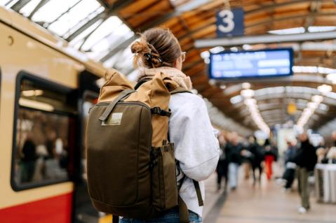 Junge Frau mit Rucksack am Bahnhof