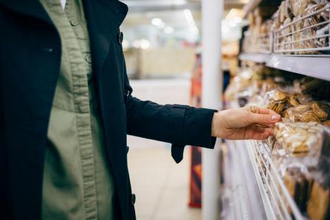 Frau wählt Kekse im Supermarktregal aus