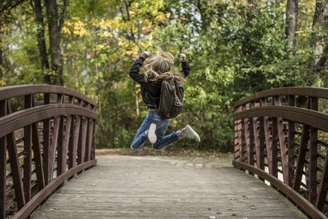 Kind mit Rucksack auf Brücke