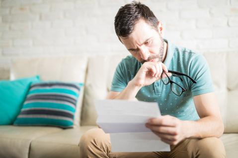 Mann sitzt auf Sofa und liest einen Brief