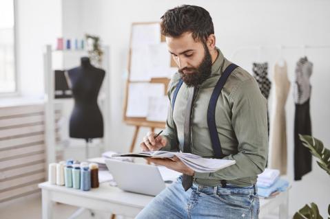 Mann mit Skizzenheft in Modeatelier