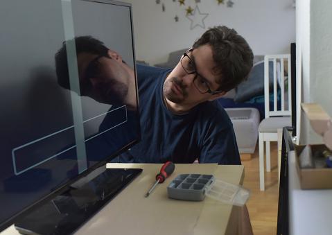 Mann schaut auf Fernseher mit schwarzem Bildschirm