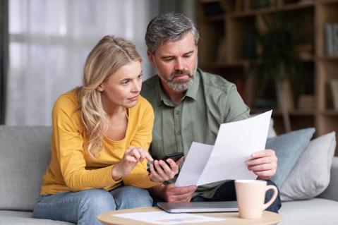 Verheiratetes Paar mittleren Alters plant gemeinsam Budget, liest Papiere und berechnet Ausgaben