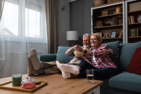 Paar sitzt auf Sofa und schaut Film mit Popcorn