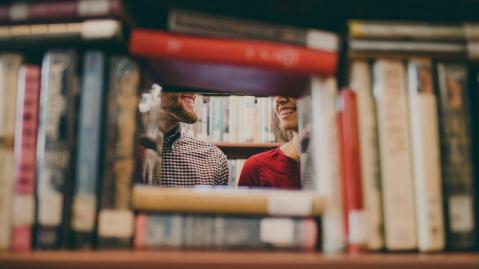 Junges Paar zu sehen durch ein Bücherregal