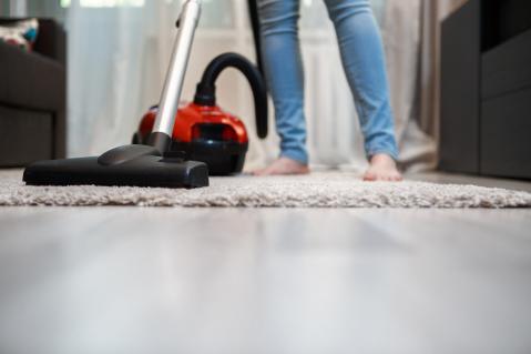 Person mit Staubsauger auf einem Teppich