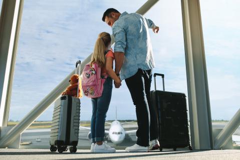 Vater und Tochter für Pauschalreise mit Koffern am Flughafen