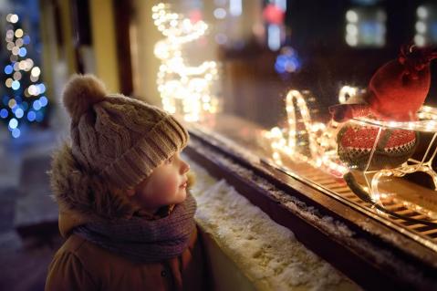 Kind an einem Schaufenster mit Weihnachtsdekoration