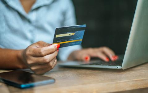 Frau bezahlt mit Kreditkarte am Laptop