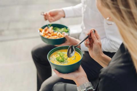 Zwei Personen löffeln Suppe aus einer Mehrwegschale