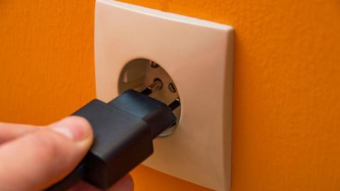 Hand steckt einen Stecker in Steckdose 